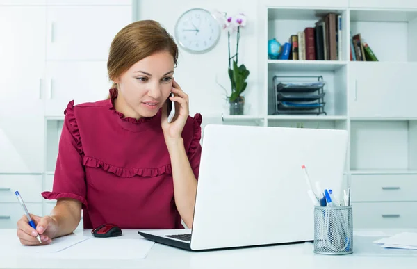 Vrouw op telefoon - laptop Stockfoto