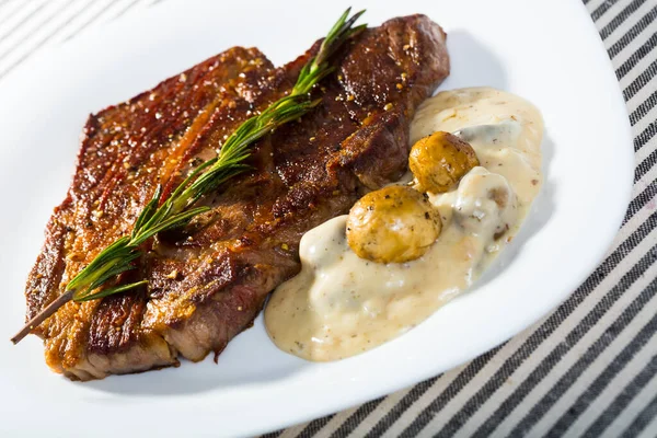 Rundsteak met champignonsaus tak van rozemarijn op witte plaat — Stockfoto