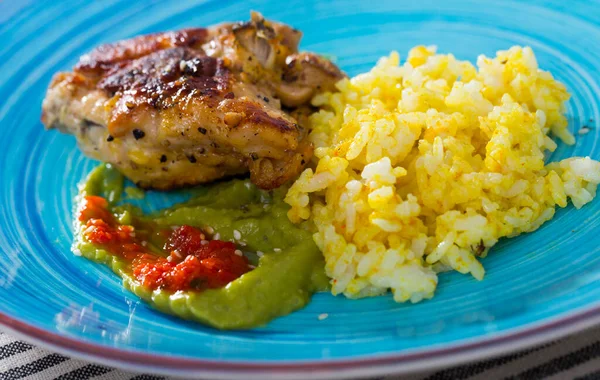 Закрыть рис с куриными бёдрами, красными и зелеными соусами на тарелке — стоковое фото