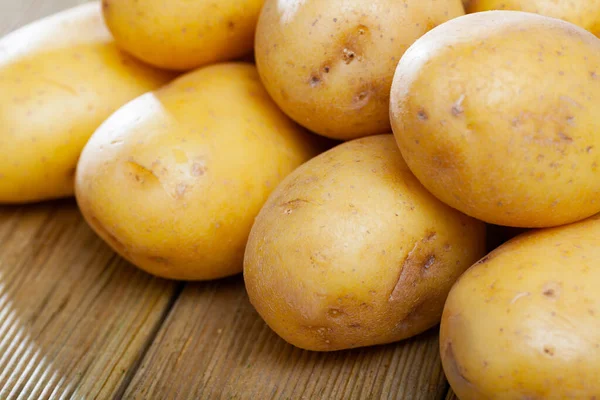 Batatas jovens frescas cruas na mesa de madeira na cozinha doméstica — Fotografia de Stock