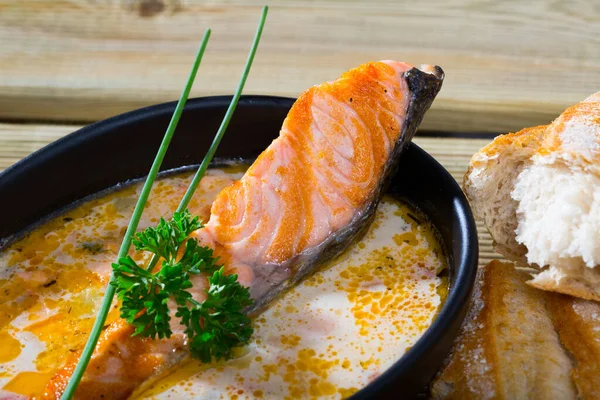 Delicious cream soup with salmon, served in bowl with bread at table — Stock Image Delicious cream soup with salmon, served in bowl with bread at table Royalty Free Stock Images