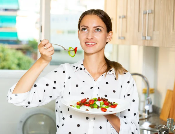 Girl tasting vegetable salad at kitchen — Stock Photo, Image