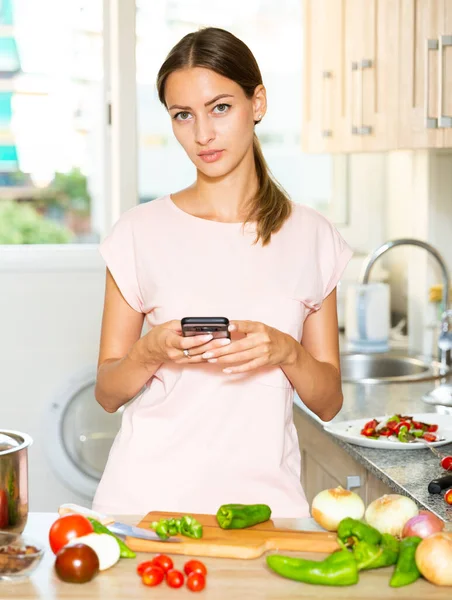 Νοικοκυρά χρησιμοποιώντας smartphone κατά τη διάρκεια της μαγειρικής — Φωτογραφία Αρχείου