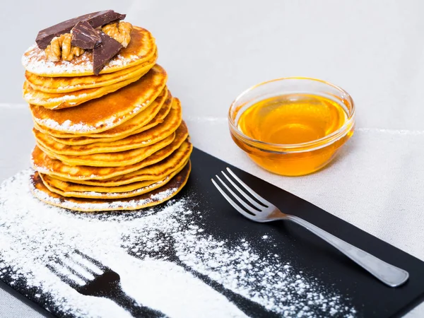 Stack of tasty pancakes served with honey, chocolate and powdered sugar — Stock Photo, Image