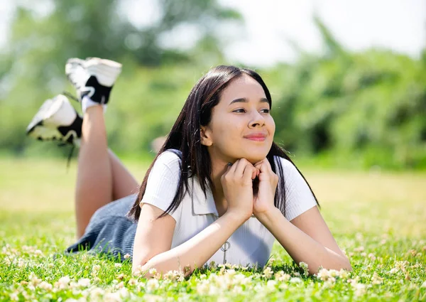 Sonriente adolescente brasileño mientras está acostado en el parque verde de verano —  Fotos de Stock