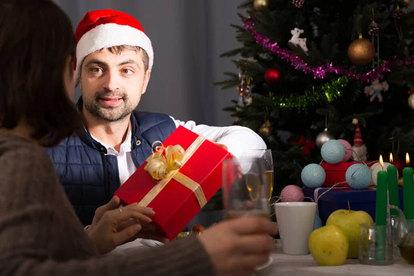 Man met hoed geeft cadeau aan vrouw met Nieuwjaar diner — Stockfoto