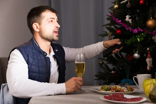 Мужчина празднует Новый год с шампанским и смотрит телевизор — стоковое фото