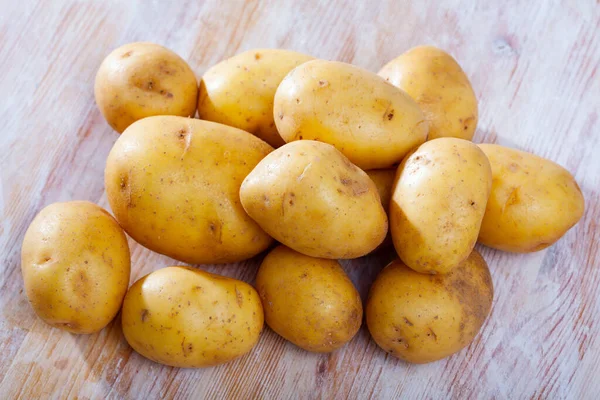 Pilha de batatas cruas na mesa de madeira na cozinha doméstica — Fotografia de Stock