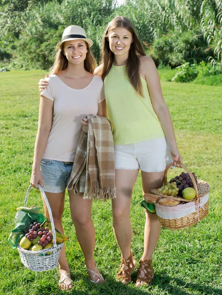 Mulheres positivas segurando cestas procurando lugar para piquenique — Fotografia de Stock