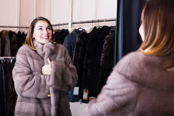 Laughing girl deciding on the choice of fur coat — Stock Photo, Image