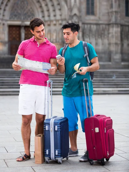 Due amici con valigie stanno camminando con mappa e guida-libro — Foto Stock