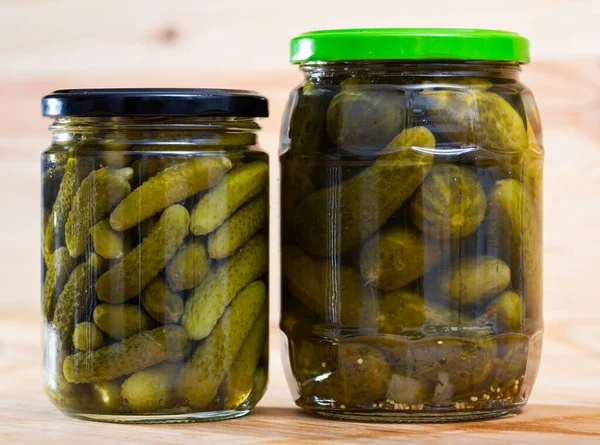 Pickled cucumbers with spices in glass jar on a wooden surface — Stock Photo, Image