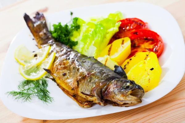 Deliciously baked whole trout with potatoes, tomatoes and greens — Stock Photo, Image