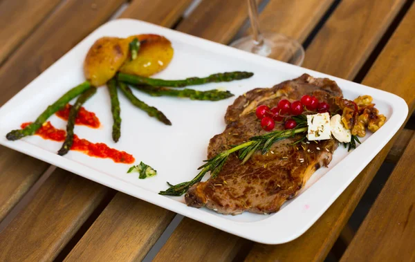 Fried beef loin with vegetables and red currant on wooden background — Stock Photo, Image