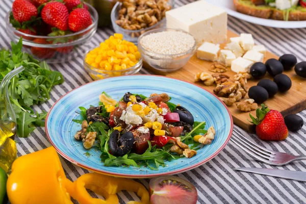 Salat mit Rucola, Oliven, Feta-Käse, Mais und Walnüssen und seinen Zutaten — Stockfoto