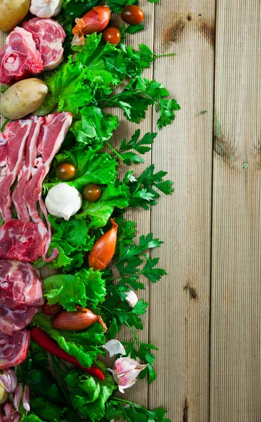 Carne di montone cruda, verdure, erbe su superficie di legno — Foto Stock