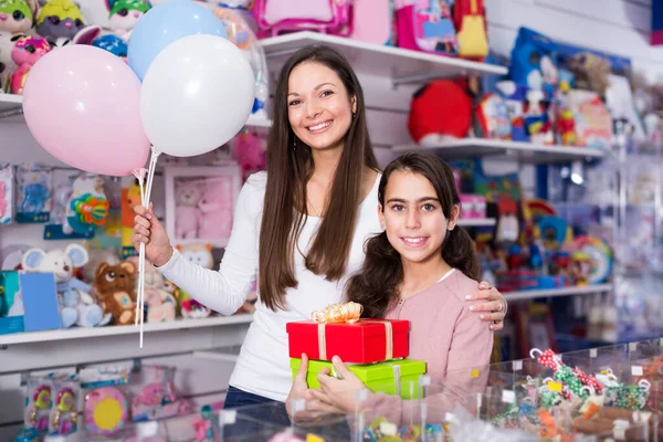 Gelukkige vrouw en dochter met geschenken en ballonnen in de winkel — Stockfoto