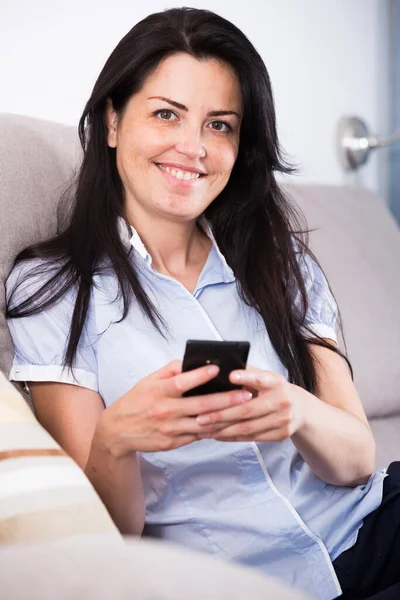 Smiling young female chatting in mobile phone — Stock Photo, Image