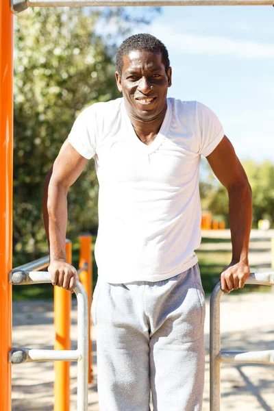 Aktif Afrikalı Amerikalı adam parktaki barfiks barında antrenman yapıyor. — Stok fotoğraf