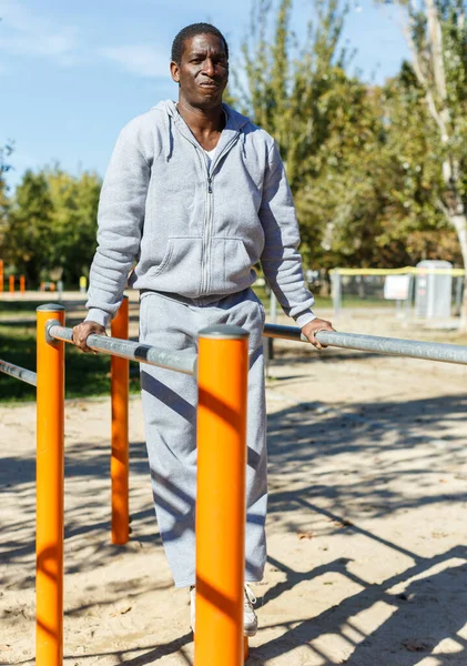 Athletic african american male performs warm-up exercises at chin-up bar — Stock Photo, Image