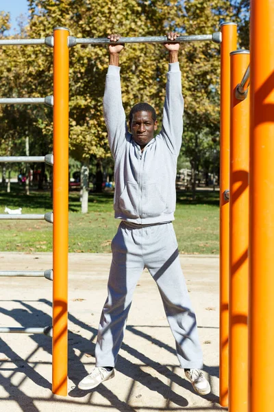 Jovens do sexo masculino treinando diferentes exercícios no chin-up bar no parque ao ar livre — Fotografia de Stock