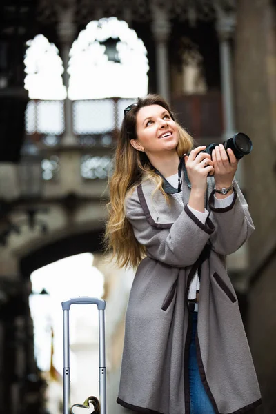 Dziewczyna trzyma kamerę w rękach i fotografuje w mieście — Zdjęcie stockowe