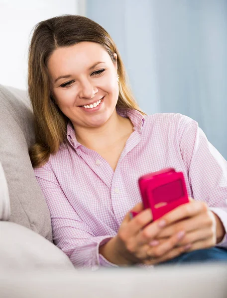 Mujer joven está sentada y usando su teléfono — Foto de Stock