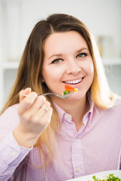 Женщина пробует свежий зеленый салат — стоковое фото