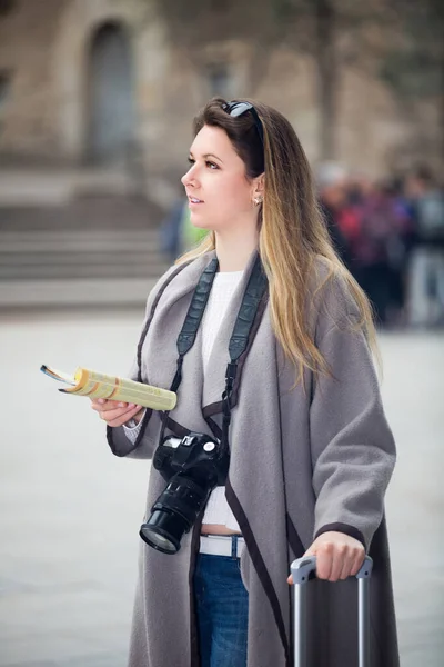 Traveling girl searching for the direction using a booklet in the town — Stock Photo, Image