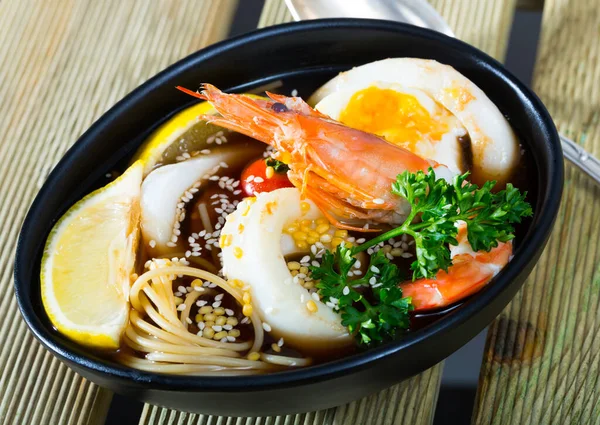 Fotografia płyty z pikantnym pan-azjatyckiej zupy z kałamarnicy, krewetki, makaron jajka i sezam — Zdjęcie stockowe