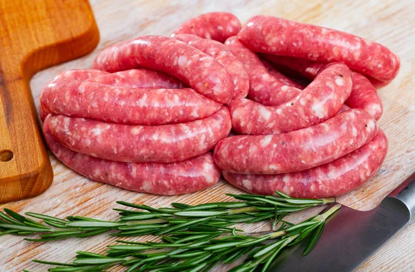 Raw meat sausages for frying on wooden desk — Stock Photo, Image