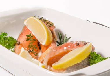 İki biftek Alabalık filetosu baharat ve beyaz arka plan üzerinde pişirme çanağı içinde limon ile