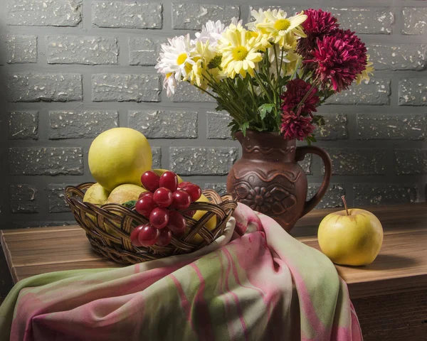 still life from bouquet of chrysanthemum with apples in basket on wooden table
