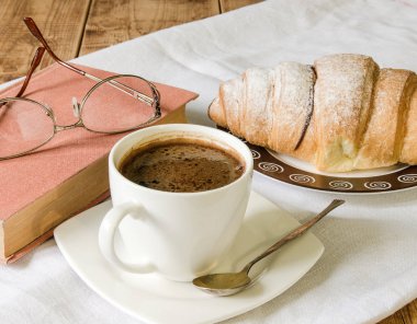 Taze kruvasan ilgili eski ahşap masa plaka ve kahve witj kitap