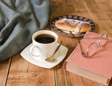 bun plaka ve kitap ile gözlük ve kareli tahta masada ile kahve