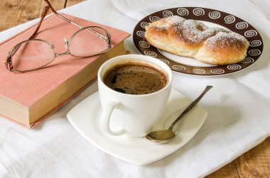 ahşap masa gözlüklerle plaka ve kitap topuz ile kahve