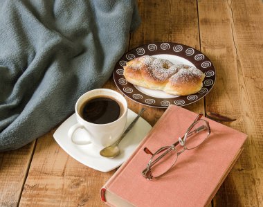 bun plaka ve kitap ile gözlük ve kareli tahta masada ile kahve