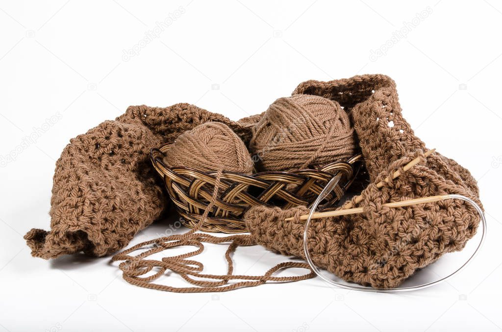 yarn and knitted fabric in a wicker basket on a white background