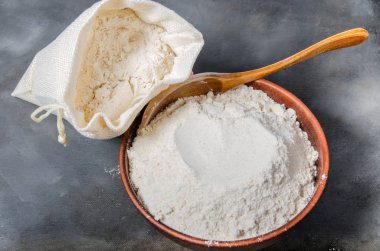 seramik kase ve koyu arka plan üzerinde kaşık tahıl unu