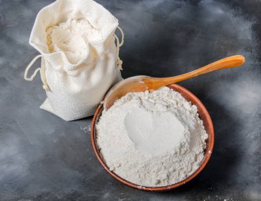 seramik kase ve koyu arka plan üzerinde kaşık tahıl unu