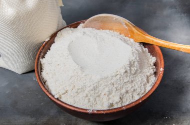 seramik kase ve koyu arka plan üzerinde kaşık tahıl unu