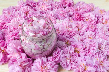 Masada pembe çay gülleri ve cam kavanozda taç yaprakları 