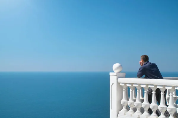 Mann steht auf Balkon und schaut aufs Meer — Stockfoto