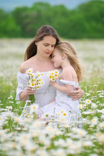 Šťastná matka a dcera v heřmánkového louce. — Stock fotografie