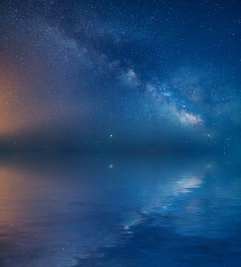 Gece gökyüzünde Samanyolu ve su yansıması. Saf doğa sahnesi.
