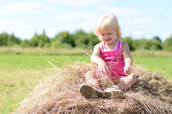 Happy baby girl laughing on summer haystack — Stock Photo, Image