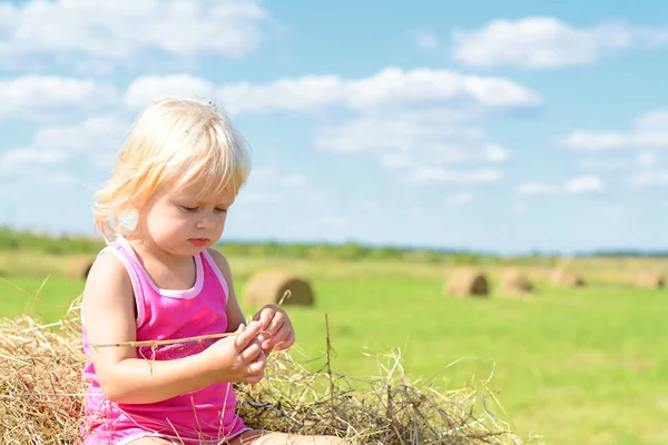 Malá venkovská dívka na slámě po sklizni — Stock fotografie