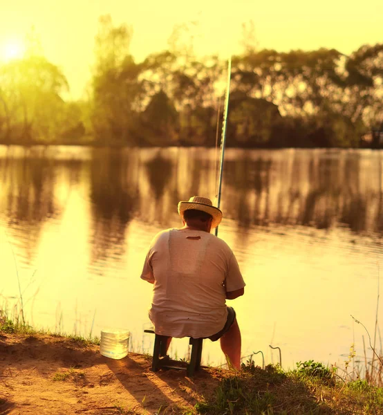 Pescador sentado na praia por do sol e pesca — Fotografia de Stock