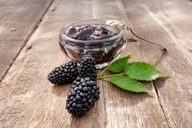 Büyük olgun böğürtlen ve böğürtlen reçeli eski ahşap bir masada