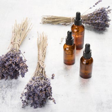 Temel lavanta yağı ve beyaz arka plan üzerinde çiçekler